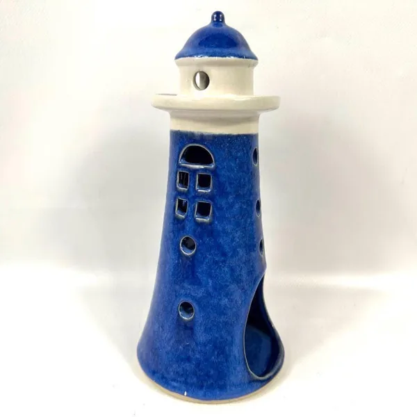 Angled side view of ceramic lighthouse showing textured cobalt glaze and circular perforation details along tower