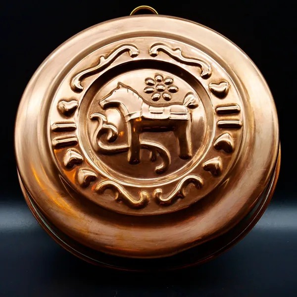 Angled three-quarter view of copper mold highlighting dimensional relief and brass loop