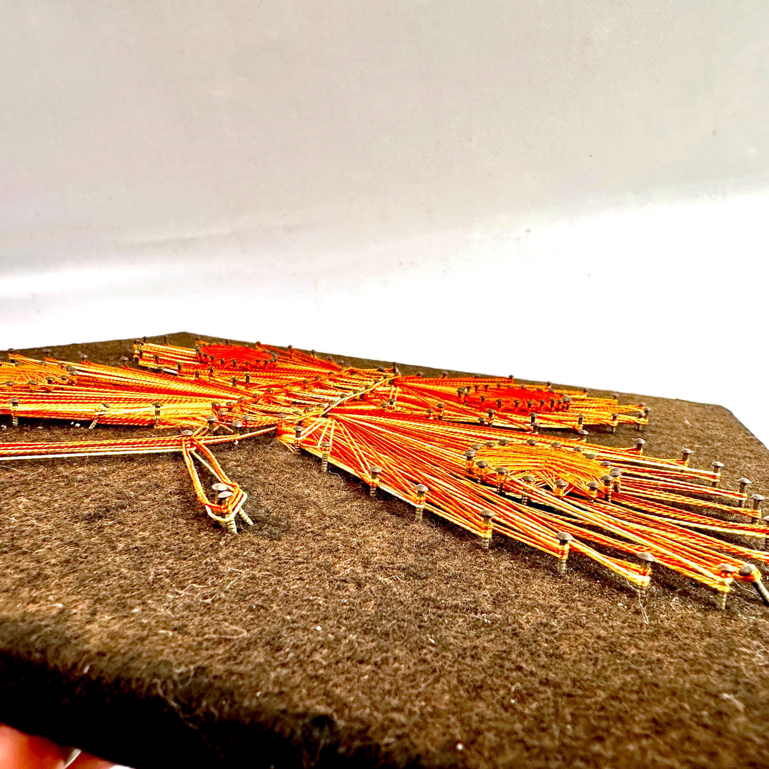 Angled view of string art butterfly showing dimension and thread relief against white background