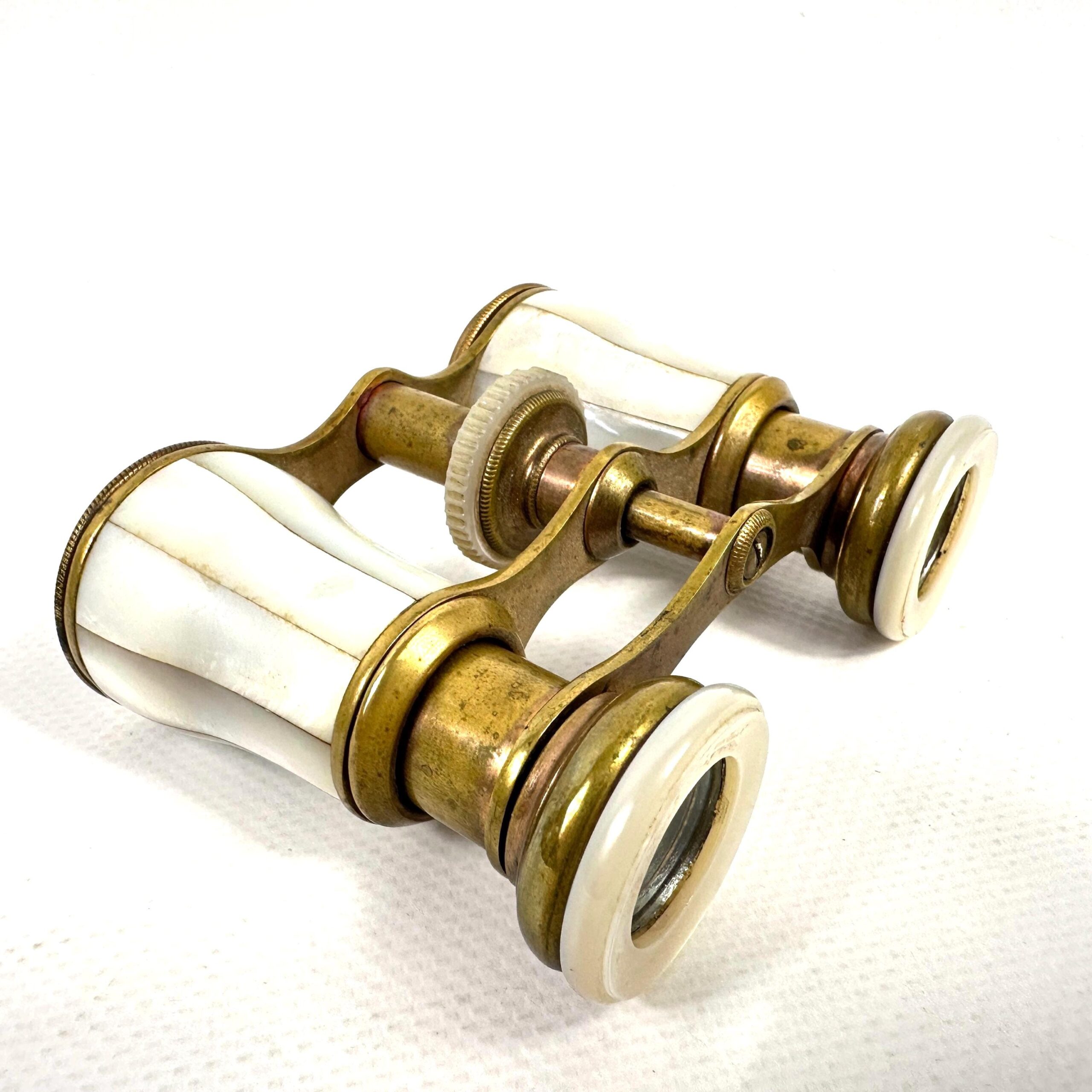 Antique brass opera glasses with mother of pearl panels, angled three-quarter view showing both optical barrels and central f