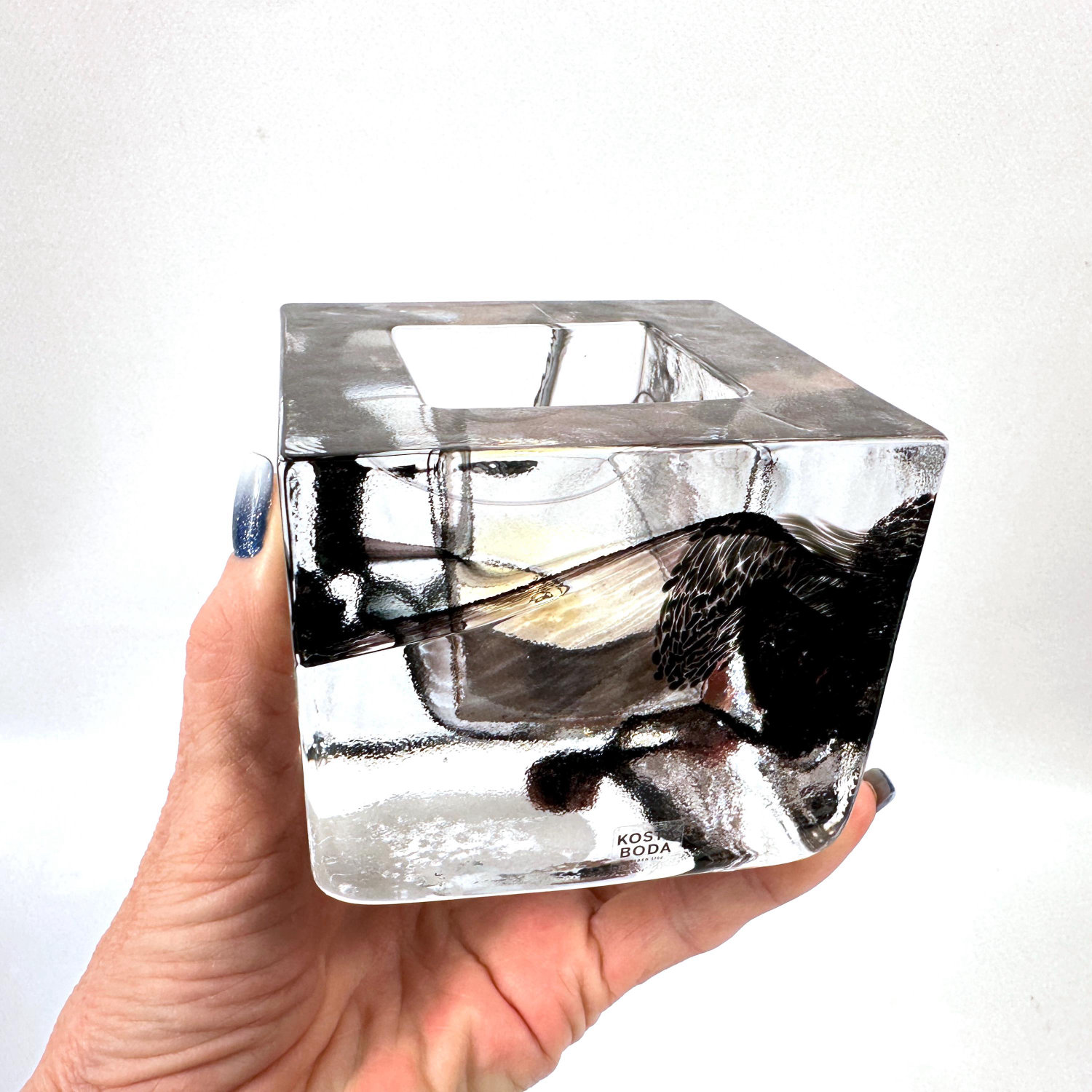 Kosta Boda votive holder held in hand, reveals compact 8.5cm cube proportions and transparent ice glass interior details