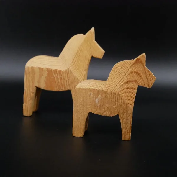 Both Dala horses positioned at angles showing graduated sizes, with wood grain visible on backs and sides