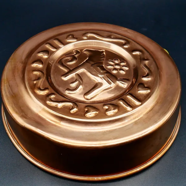 Bottom angled view of copper mold showing curved base and patinated surface texture