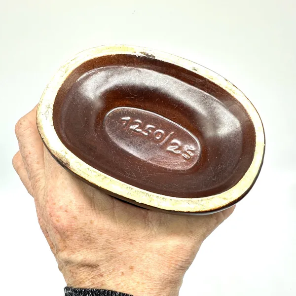 Bottom view of Scheurich vase held in hand, showing dark ceramic base with impressed maker's mark and glaze pooling