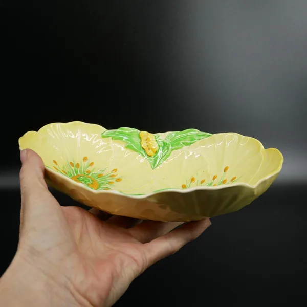 Carlton Ware Buttercup bowl held in hand from above, pale yellow ceramic with embossed petals and green leaf accents, servewa