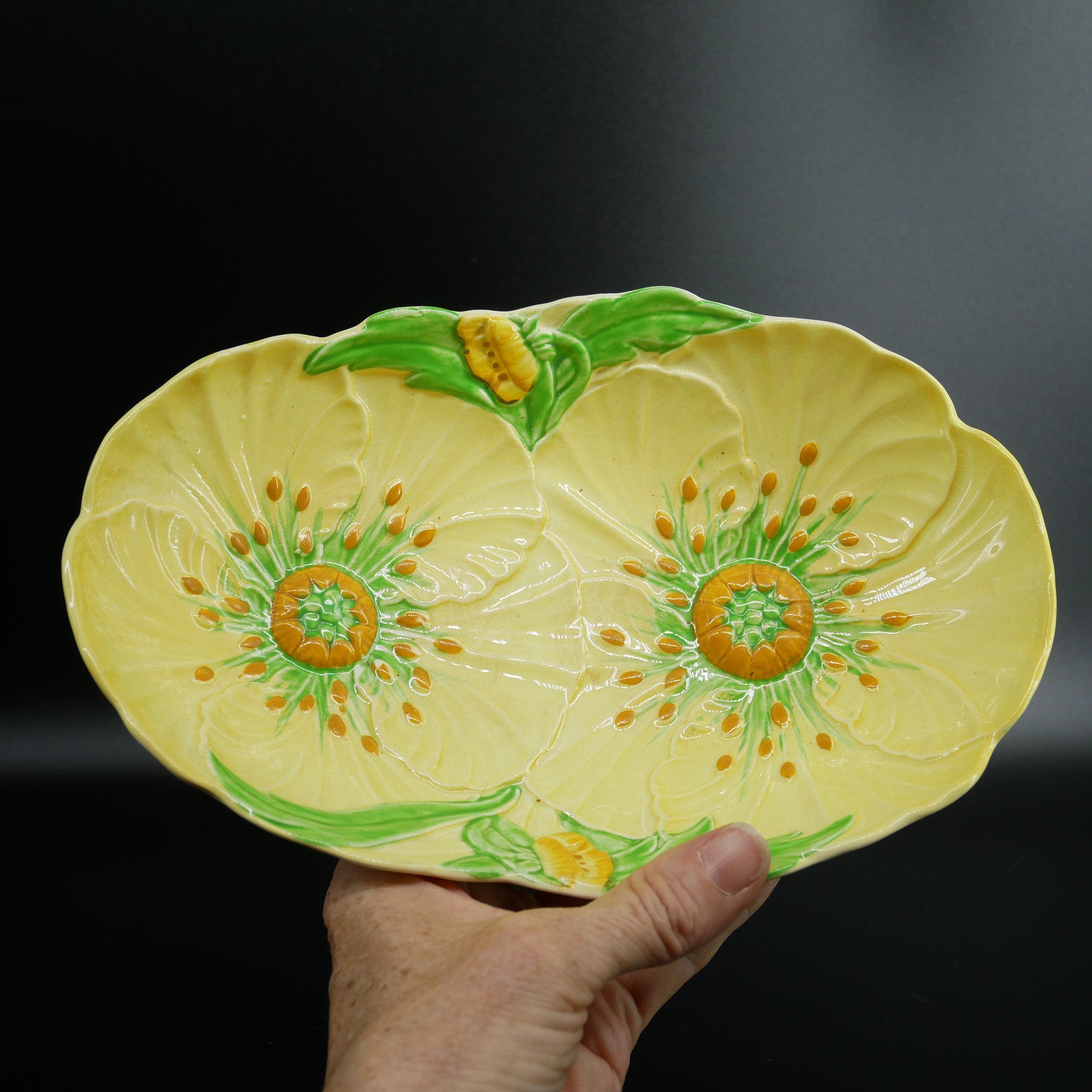 Carlton Ware Buttercup bowl held in hand, yellow embossed petals with green leaf and orange-speckled center, 1960s Australian