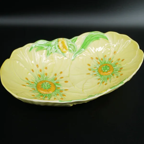 Carlton Ware Buttercup bowl low angle view, emphasizing embossed rim and dual buttercup flowers with green leaves on pale yel