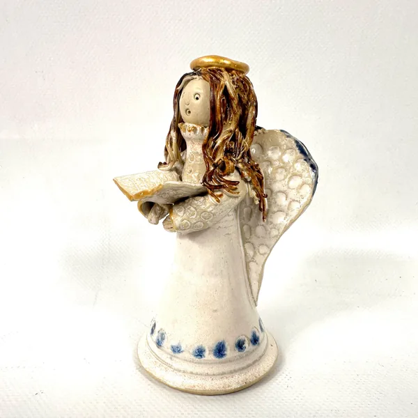 Ceramic angel figurine showing left side with spaghetti hair, textured wings, gold book detail, and cream glaze finish