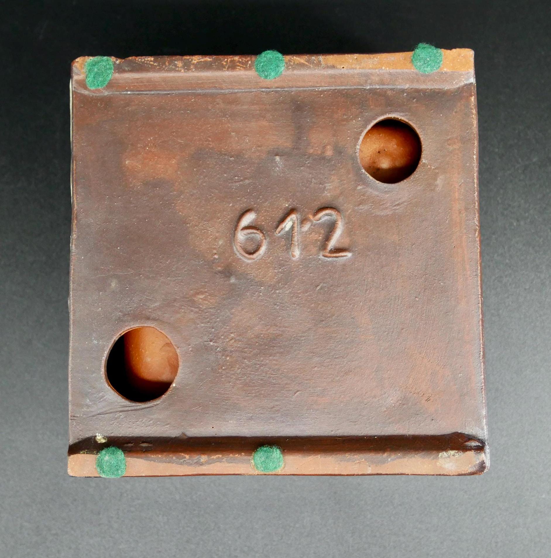 Ceramic ashtray base underside showing number stamp 612, patinated copper hardware, raised corner feet, maker's mark