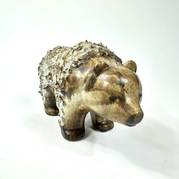 Ceramic bear sculpture angled to emphasize sculptural head and facial modeling with weathered stoneware surface details