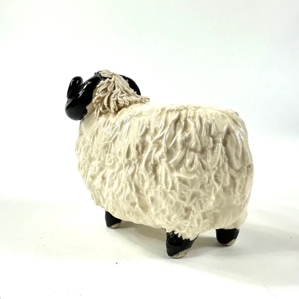 Ceramic ram figurine low angle view, emphasizing black legs and hooves, textured body looms above, folk art feel