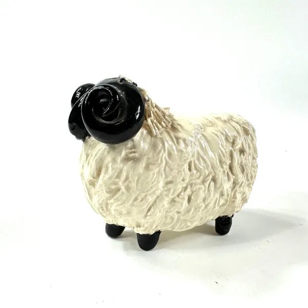 Ceramic ram figurine rear three-quarter view, textured cream fleece prominent, black horns and back legs clearly visible