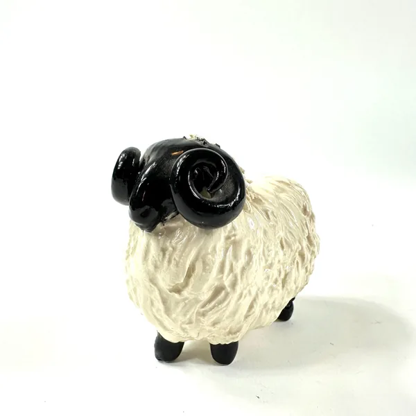 Ceramic sheep with both black horns visible, side-turned view showing textured cream body, farmhouse folk art style