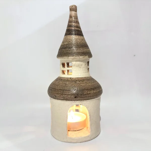 Ceramic tower interior lit from candle, golden light glowing through open doorway, textured stoneware visible, warm atmospher