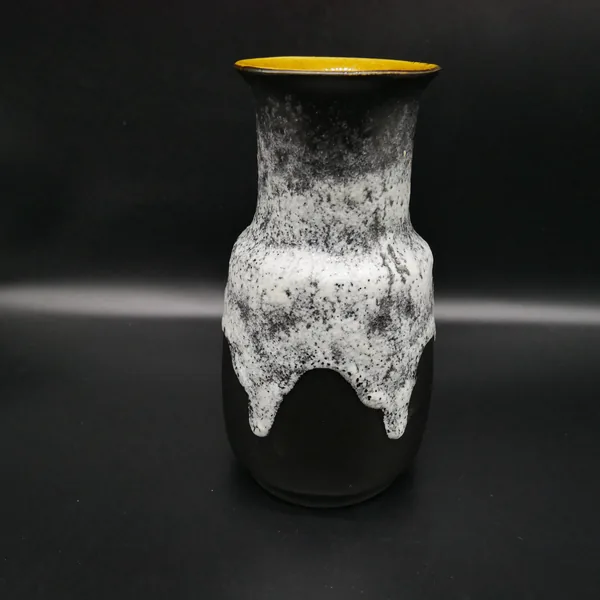 Ceramic vase three-quarter angle showing textured lava glaze asymmetry, curved body, and tapered base form