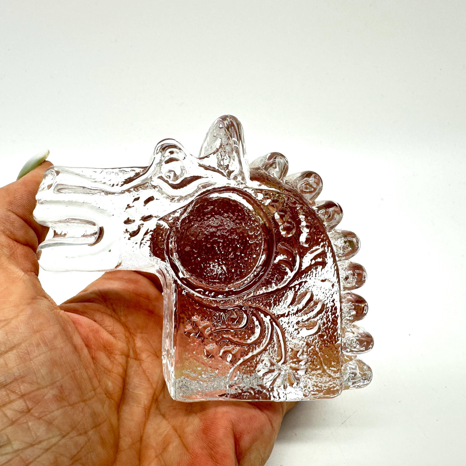 Clear art glass horse head by Bertil Vallien, held in hand, showing detailed carved mane and circular opening, 1960s Swedish 