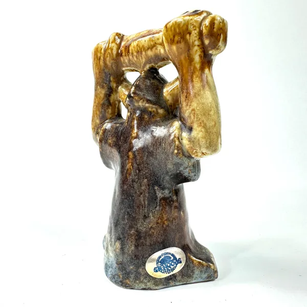 Close angled view of ceramic head and shoulders with studio pottery mark visible at base, showing glaze gradient