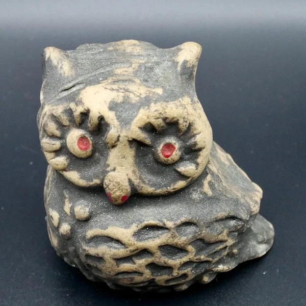 Close-up frontal view emphasizing owl's facial features with dark eye rings, colored pupils, and rust-toned nose against warm