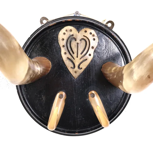 Close-up of carved bone heart motif on black wooden plaque of antique Scandinavian rack, showing folk art relief detail