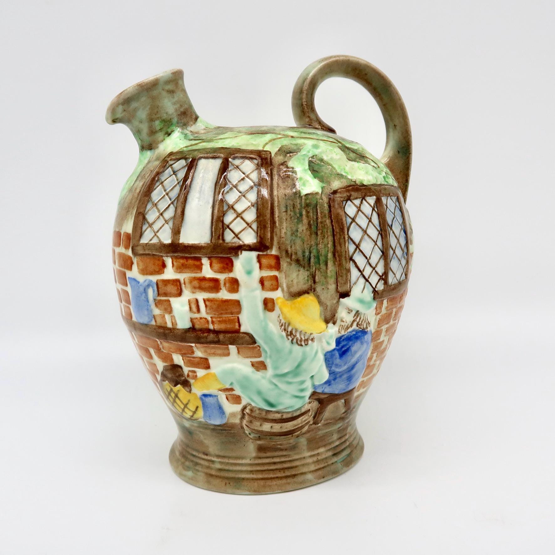 Cottageware jug full view with hand-painted figures, leaded windows, ivy relief, and brass handle, English ceramic pitcher 19