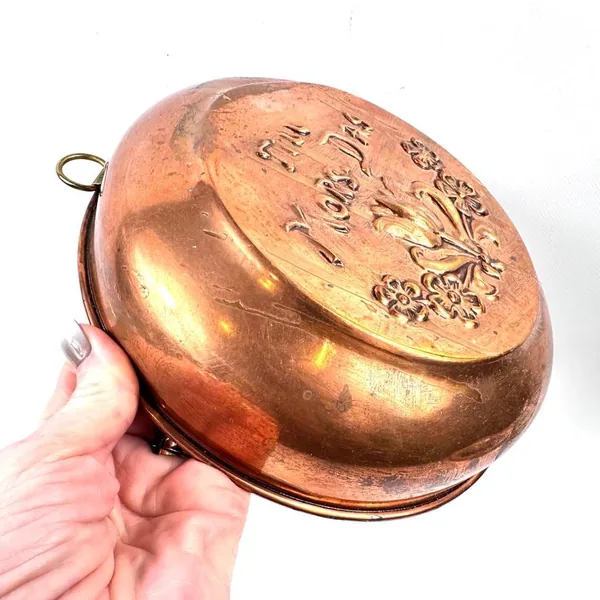 Curved copper surface in close detail revealing rich patina transitions from golden-amber to deep bronze tones