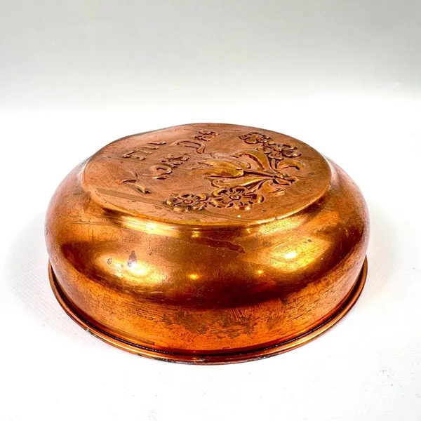 Curved copper wall plate photographed from side angle, showing generous dome shape with polished golden-brown finish