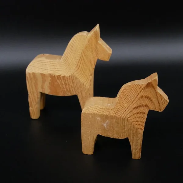 Dala horses viewed from rear angle, showing cylindrical leg construction and wood grain patterns on hindquarters and back