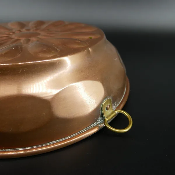 Detailed close-up of copper mold edge with brass loop and smooth curved rim