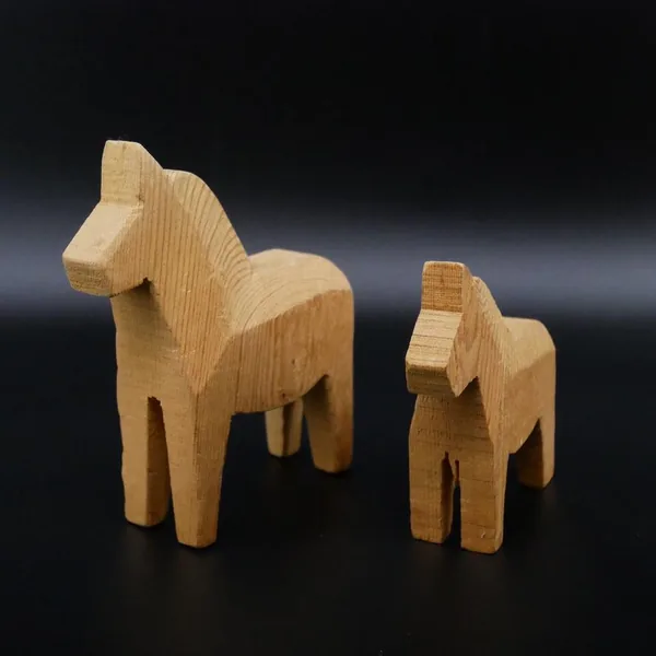 Front-facing view of carved wooden Dala horse with expressive head and block-style body, emphasizing naïve folk art charm