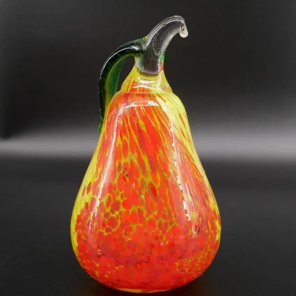 Front-facing view of Kosta Boda pear showing predominantly red lower half, yellow upper section, and leaf crown