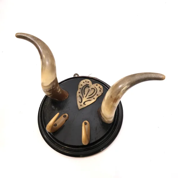 Frontal view of antique Nordic bull horn rack with symmetrical horns and carved bone heart emblem on weathered black painted