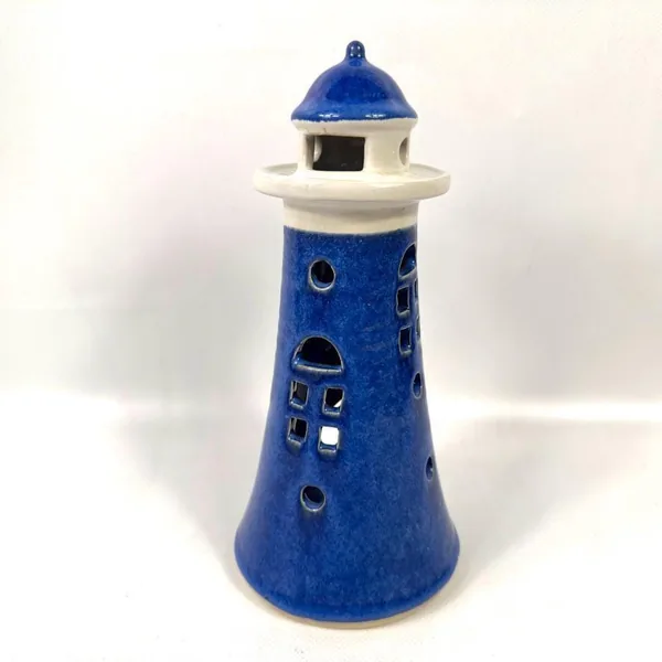 Full lighthouse candle holder photographed at eye level, showing complete form with glazed finish and cream lamp room