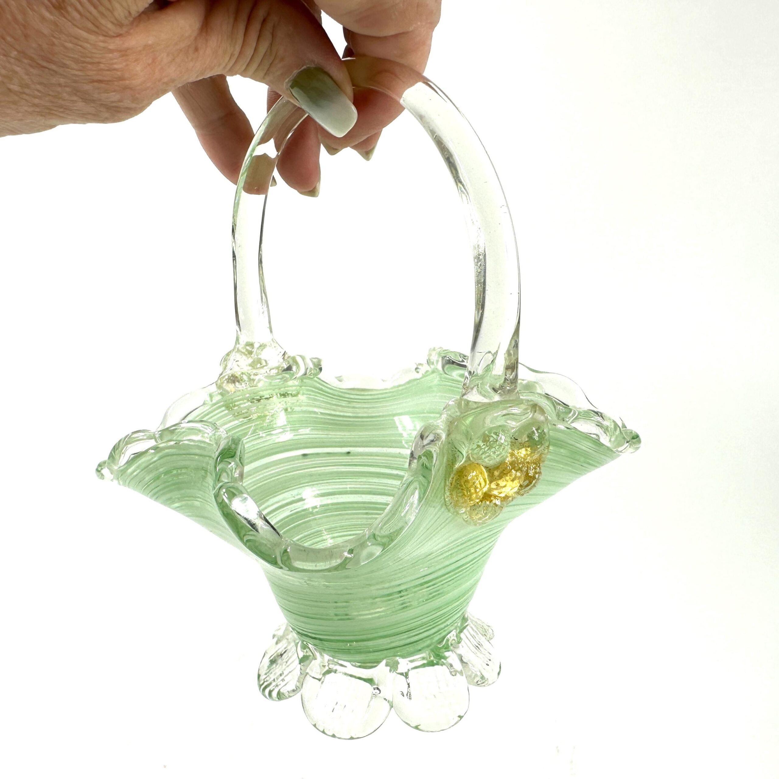Hand-blown green glass basket with clear handle, translucent swirl pattern, and gold fleck detail on one side