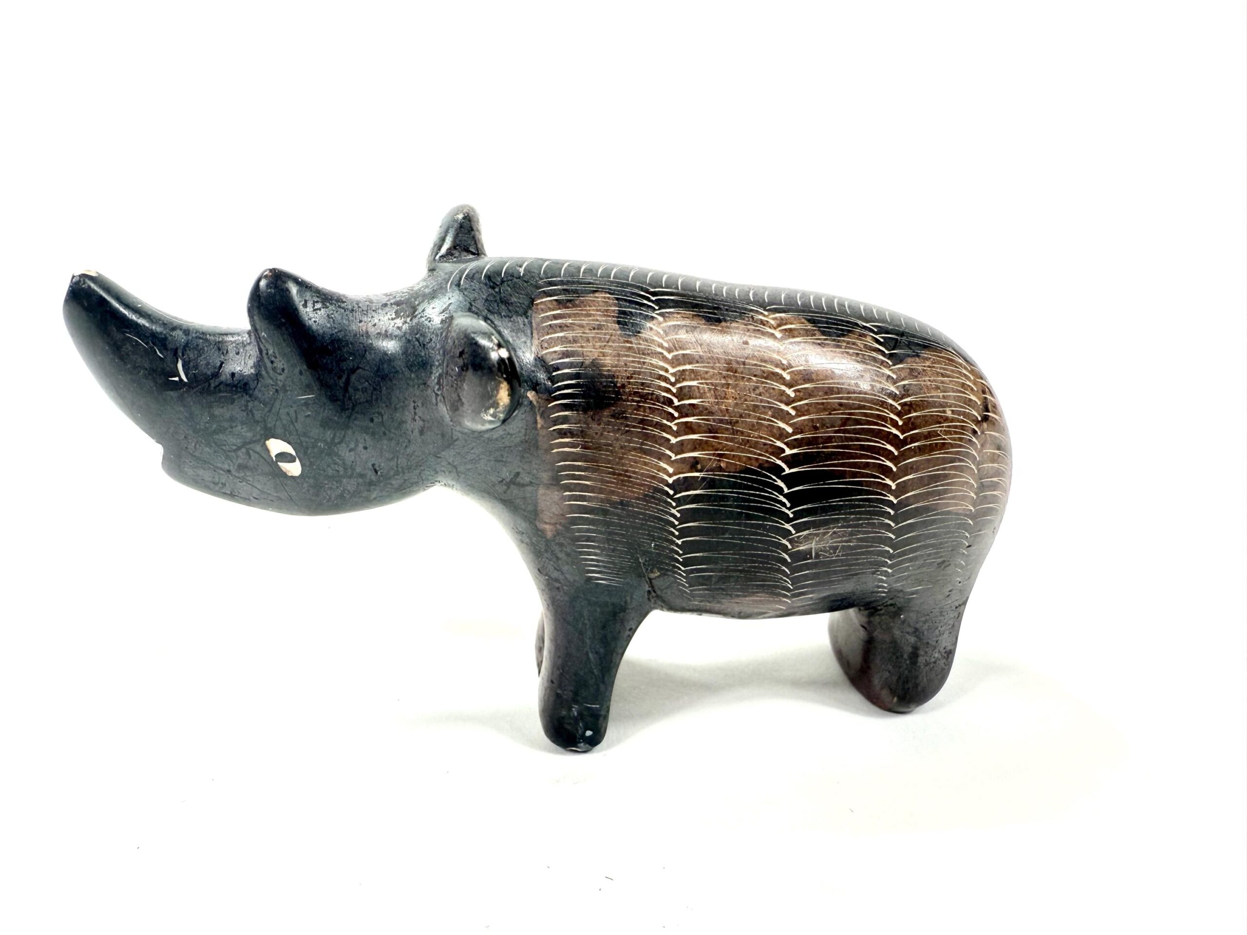 Hand-carved soapstone rhino figurine with dark stone head and natural tan crosshatch-textured body, profile view
