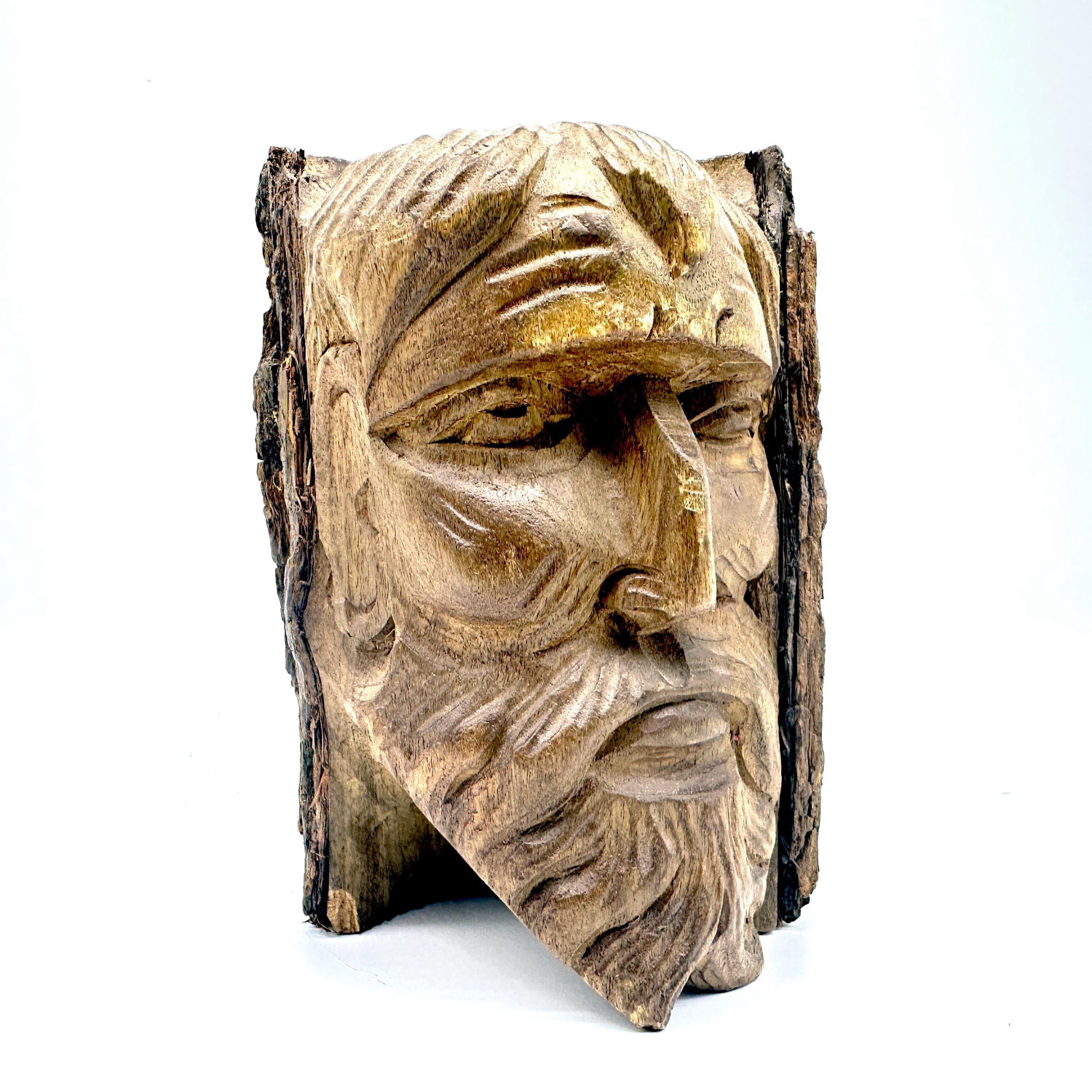 Hand-carved wooden face sculpture with bearded male visage, natural bark edges, front-facing view showing expressive eyes and
