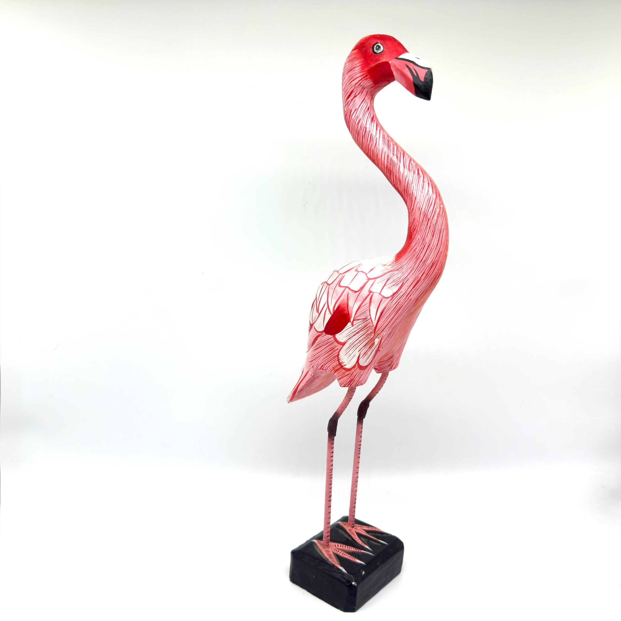 Hand-carved wooden flamingo sculpture in soft pink, tall curved neck and stylized wings, mounted on black wooden base
