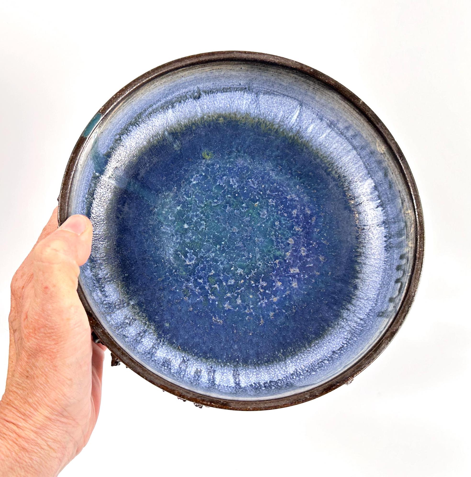 Hand-held view of vintage lava bowl showing periwinkle-blue interior glaze and scale of the 20cm diameter piece