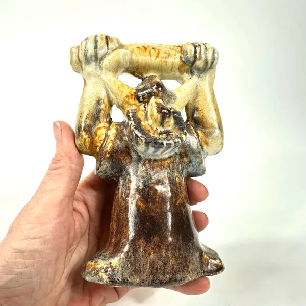 Hand holding ceramic Viking figure shows scale context, glaze detail on arms, golden upper torso, collector display