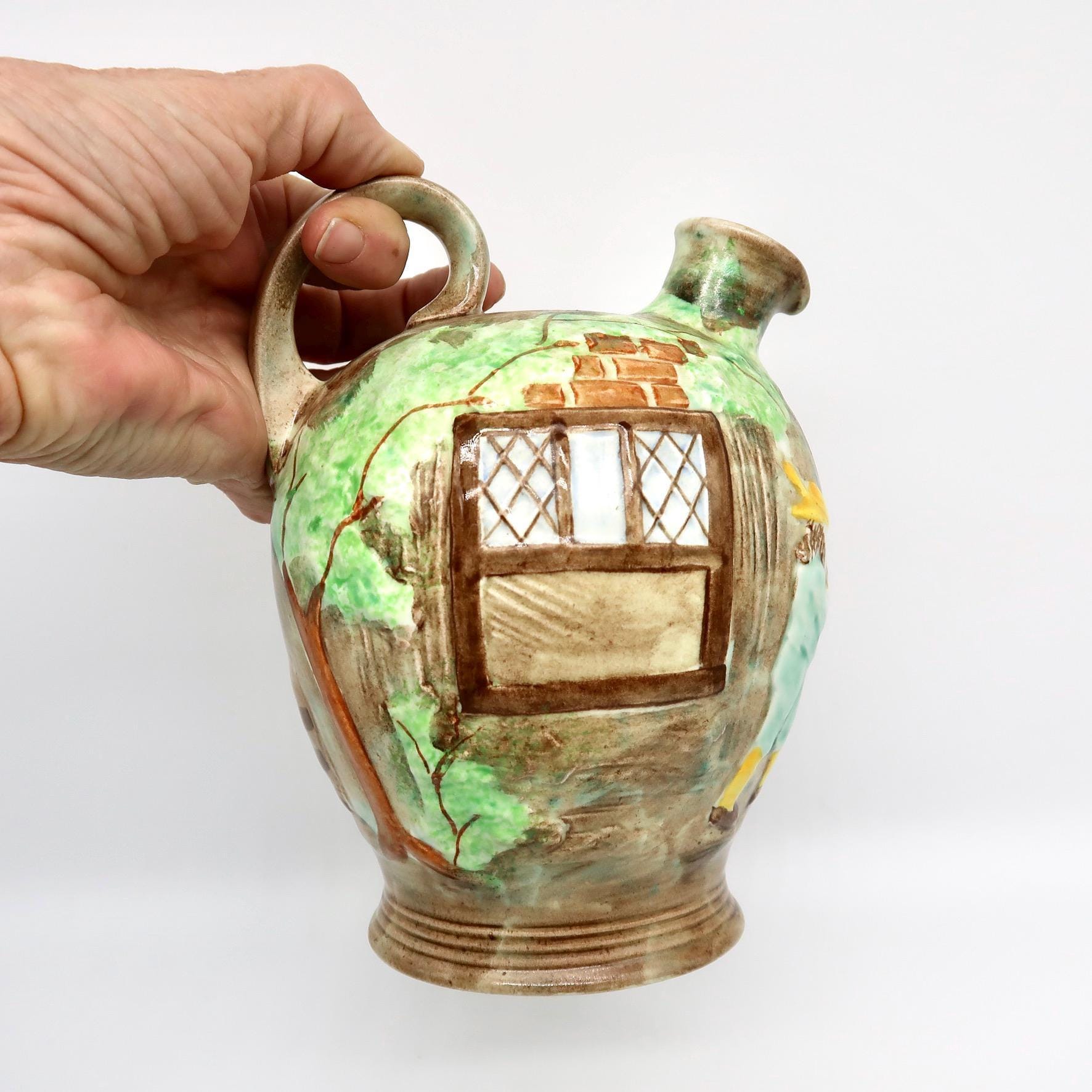 Hand holding cottageware jug, showing scale and heft of vintage ceramic pitcher, relief detail, and practical spout design
