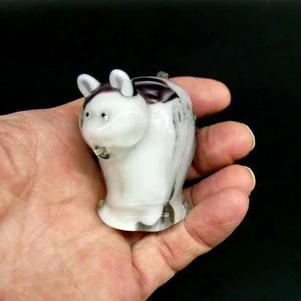 Hand holding vintage cream and black striped glass cat figurine, showing true compact size and sculptural proportions