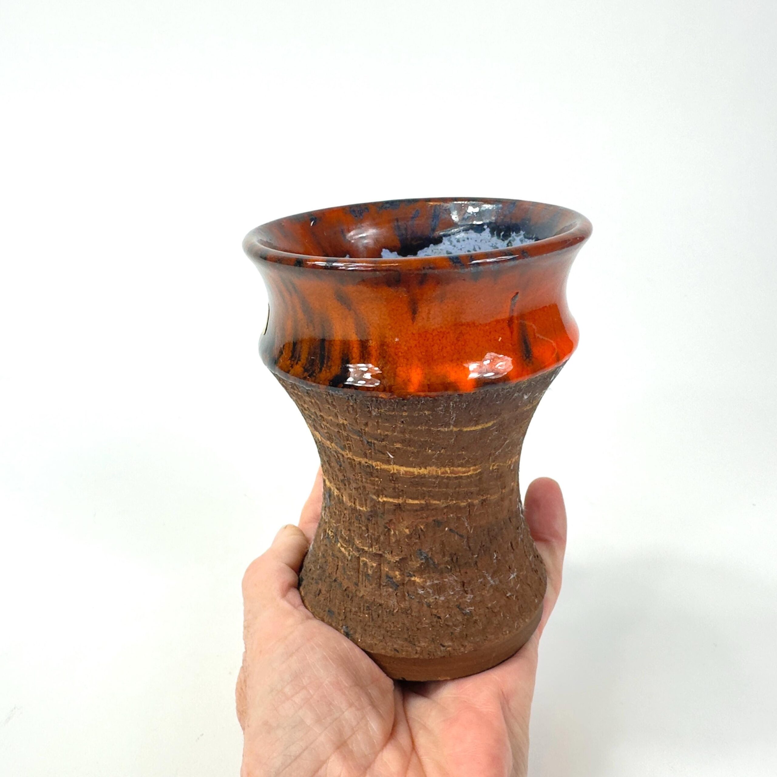 Hand holding vintage Danish pottery vase, showing scale and weight of 1970s stoneware piece with drip glaze