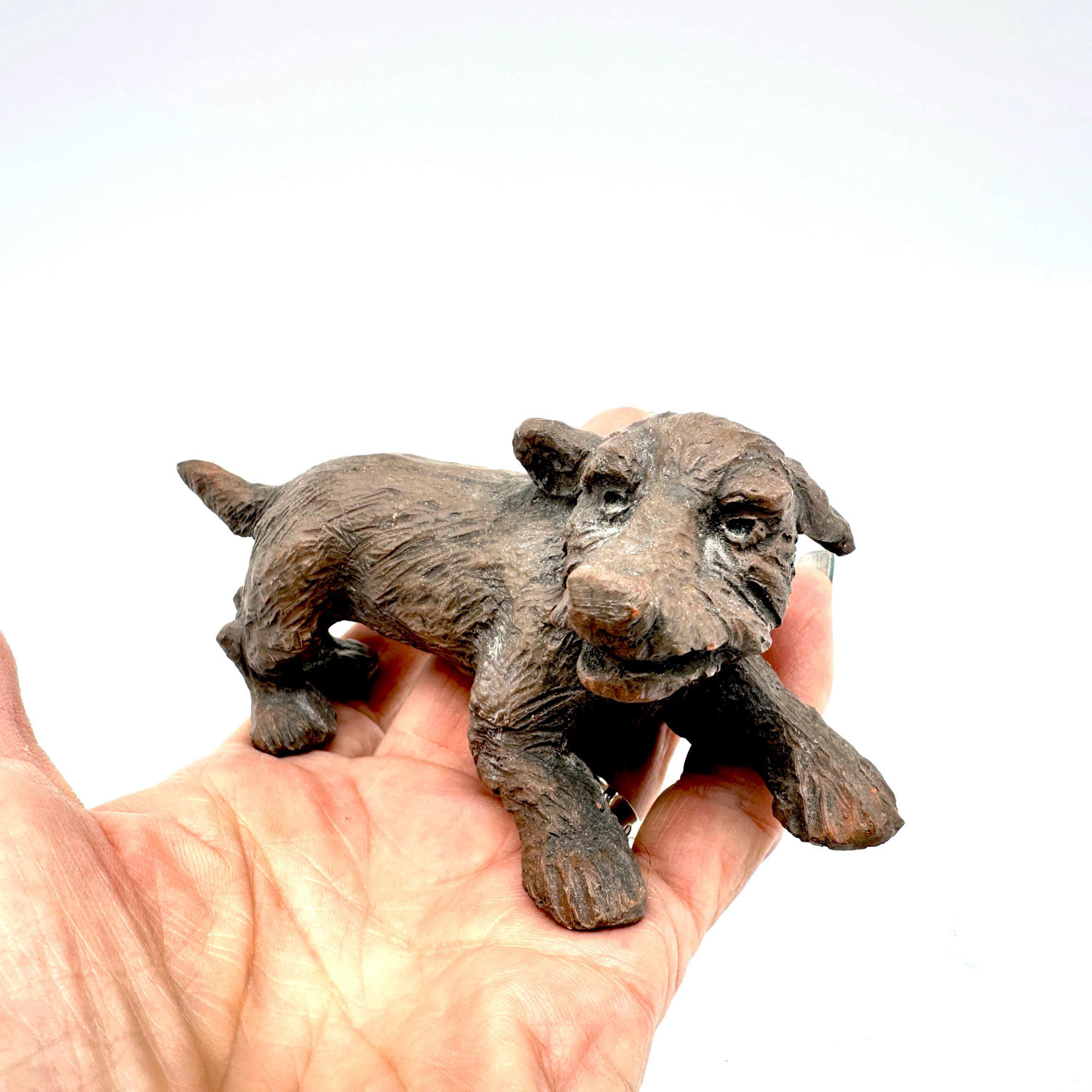 Hand-modeled ceramic dog close-up facial features, expressive eyes, snout detail, surface patina in natural light