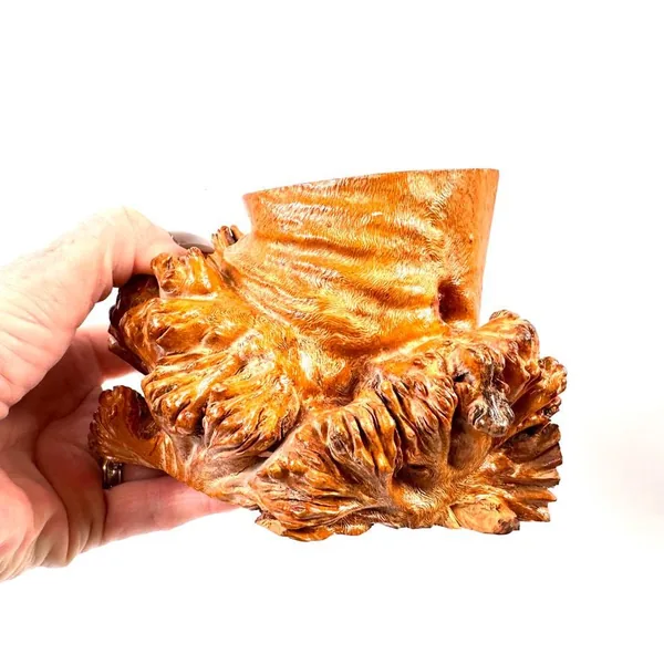 Handheld view of burl wood bookend in hands, showing scale, weight impression, intricate carved texture, and lacquered warmth