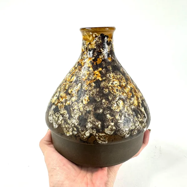 Hands cradling golden-glazed vase showing three-dimensional surface relief and tactile texture