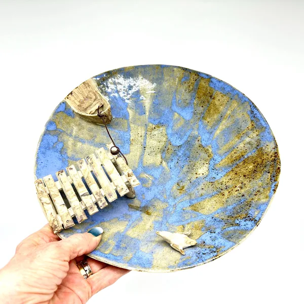 Hands-on scale perspective of blue studio pottery bowl held in palm, showing boat detail and overall size of this handcrafted