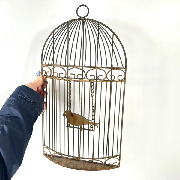 Held birdcage showing hand-scale reference, metal weight, and textured patina finish with authentic aging marks