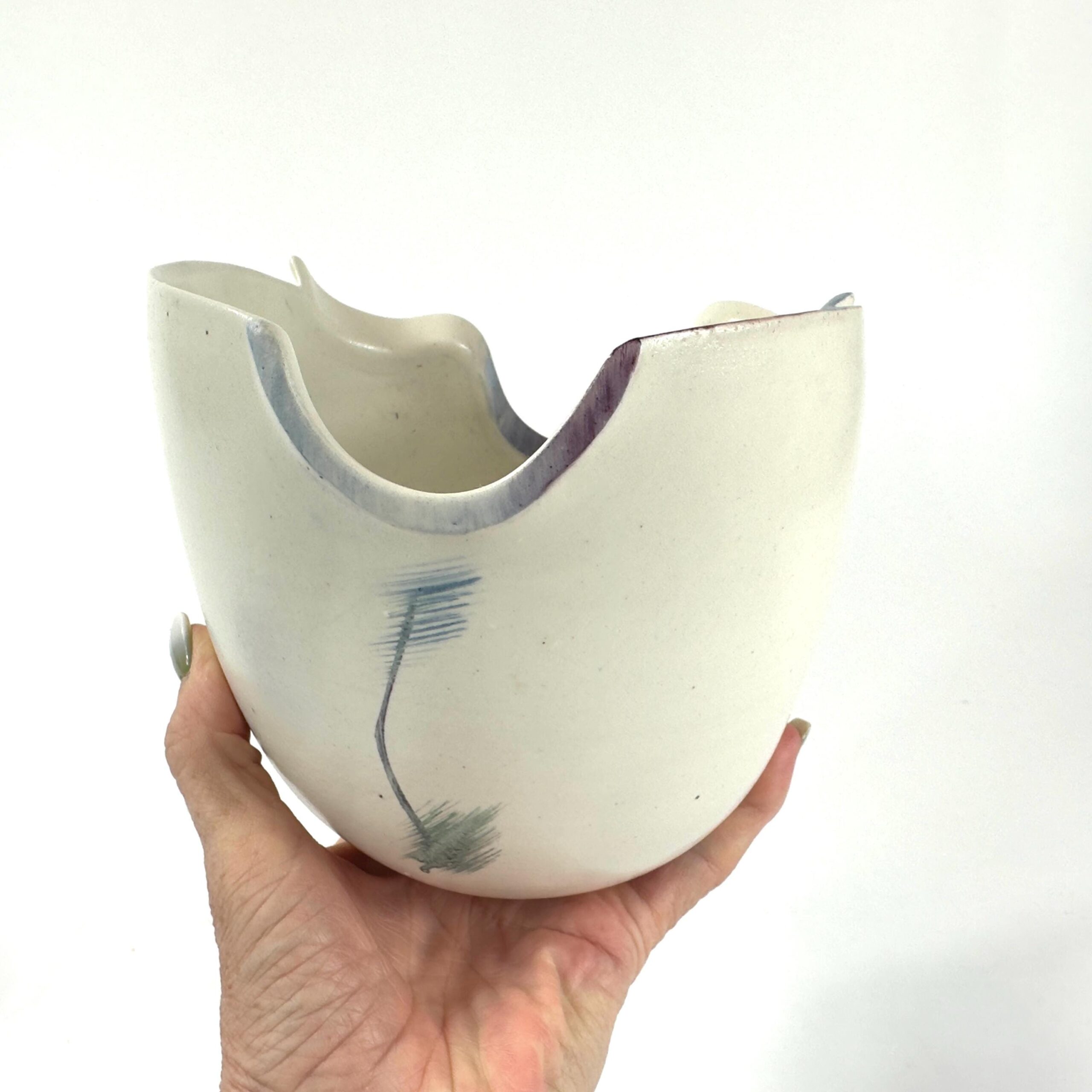 Held in hand showing scale and weight of stoneware bowl, cream glaze with abstract blue and soft green brushstrokes, size per