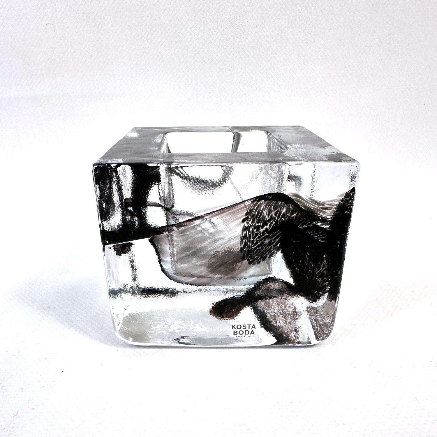 Kosta Boda ice block votive, side profile angle showing embedded black glass forms and translucent clarity