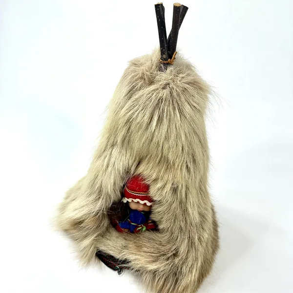 Lapland Sami doll teepee showing doll's face with red embroidered hat and handstitched fabric clothing from side angle