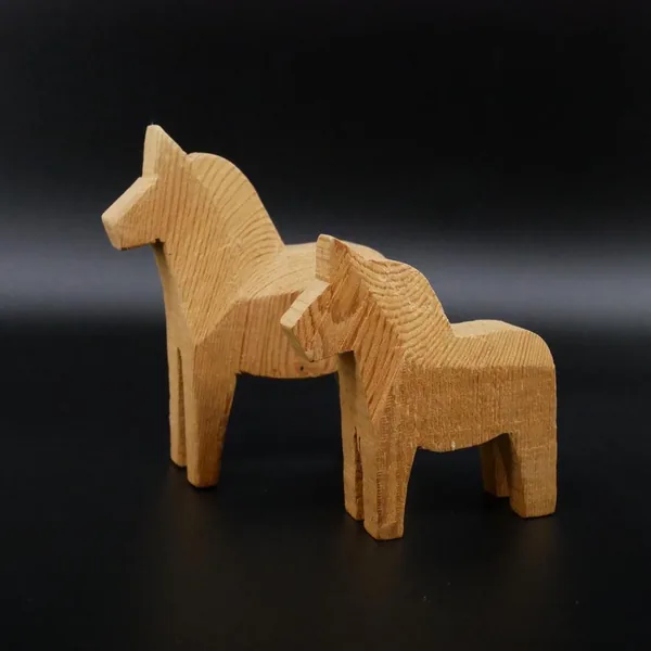 Larger Dala horse carved wood figurine with pronounced mane detail and sturdy cylindrical legs, shown in profile view